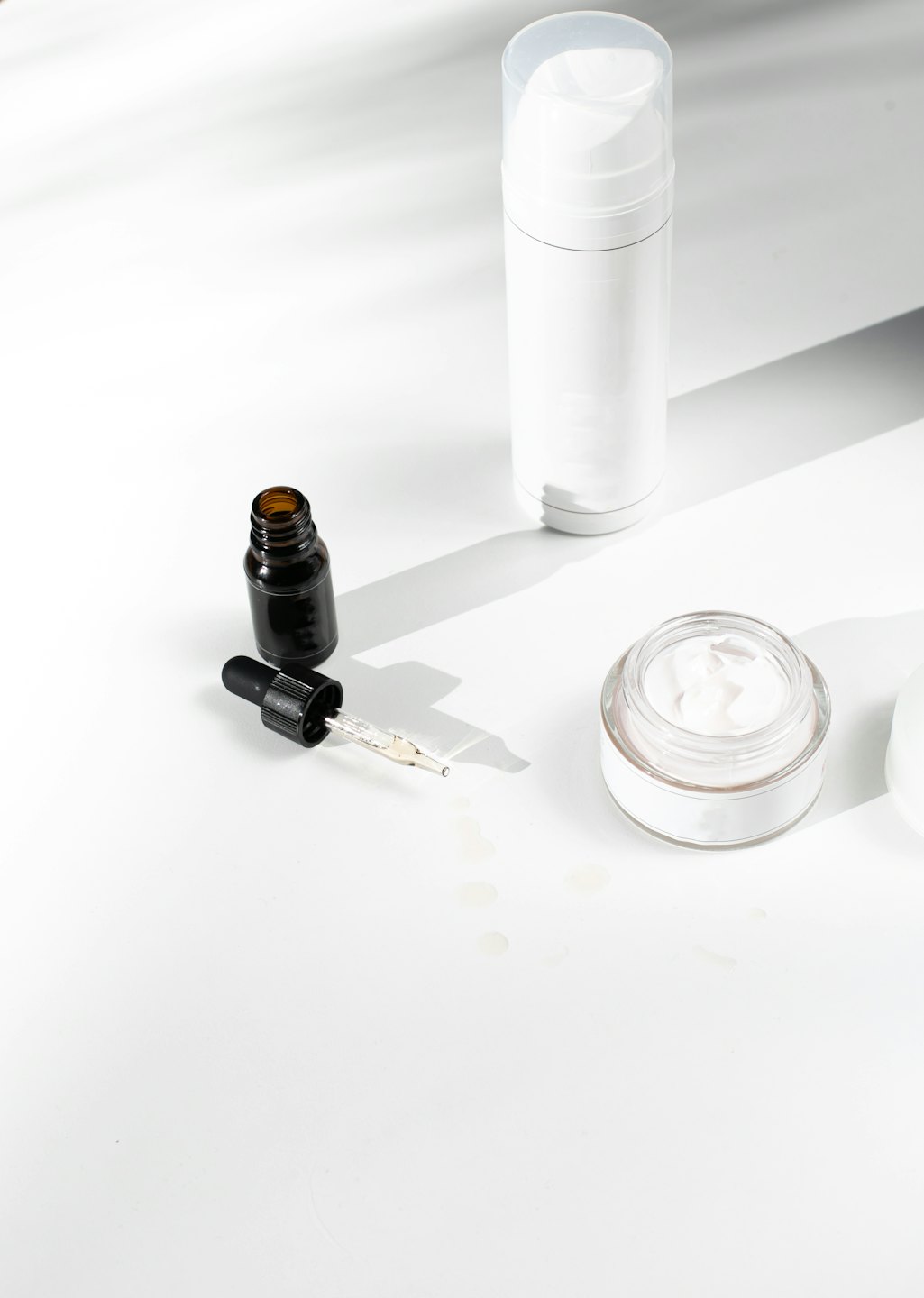 Skincare bottles and jar arranged on a white surface.