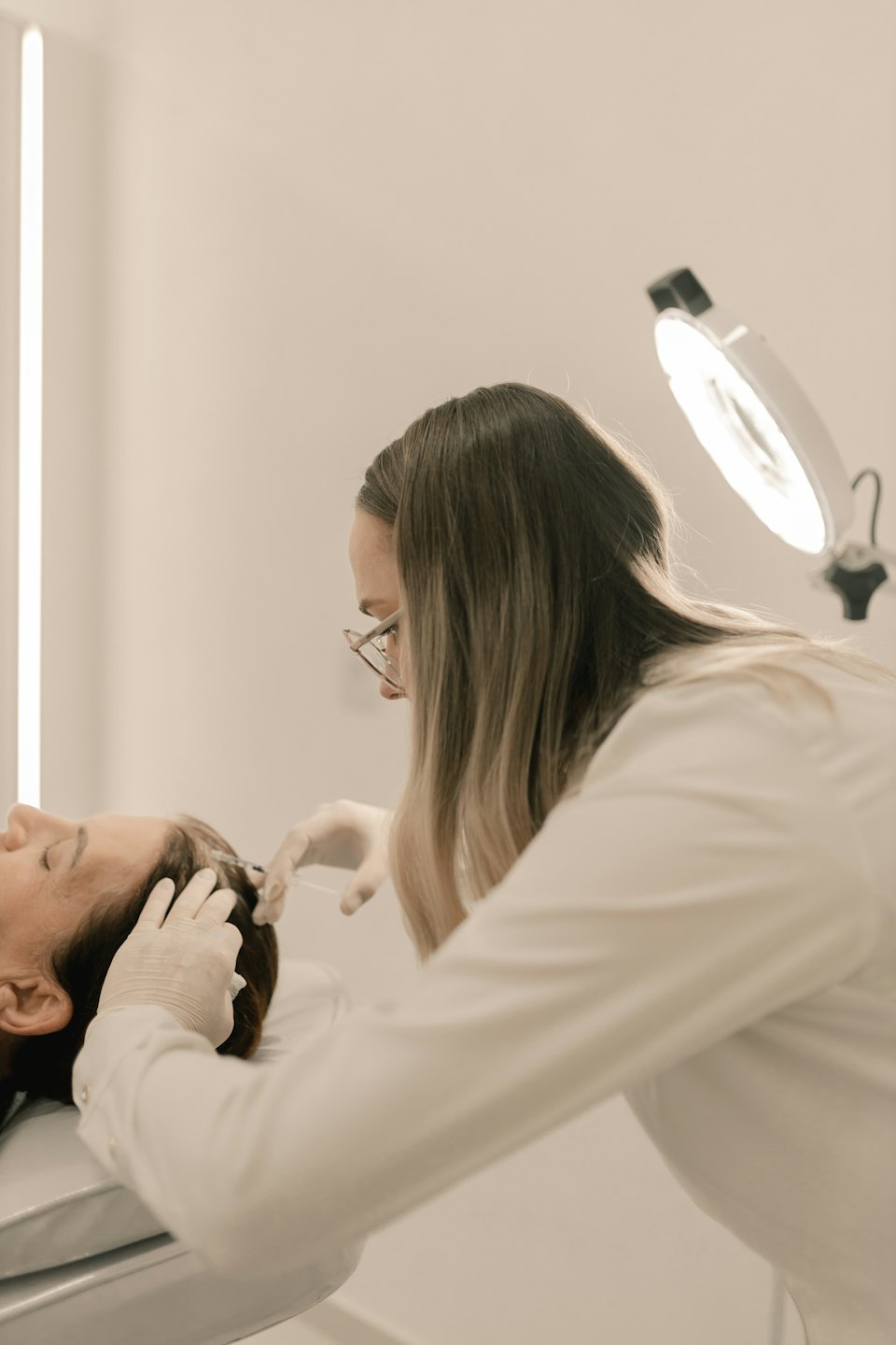 Professional performs scalp injection procedure in clinic.
